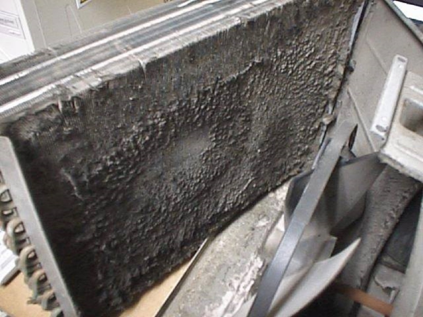 Soot-blackened evaporator coil pulled for cleaning during a maintenance visit