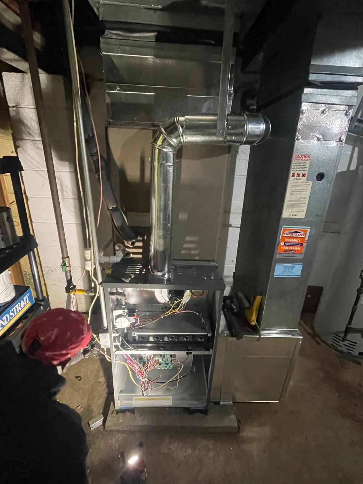 Climate Mechanics technician servicing a gas furnace in a basement