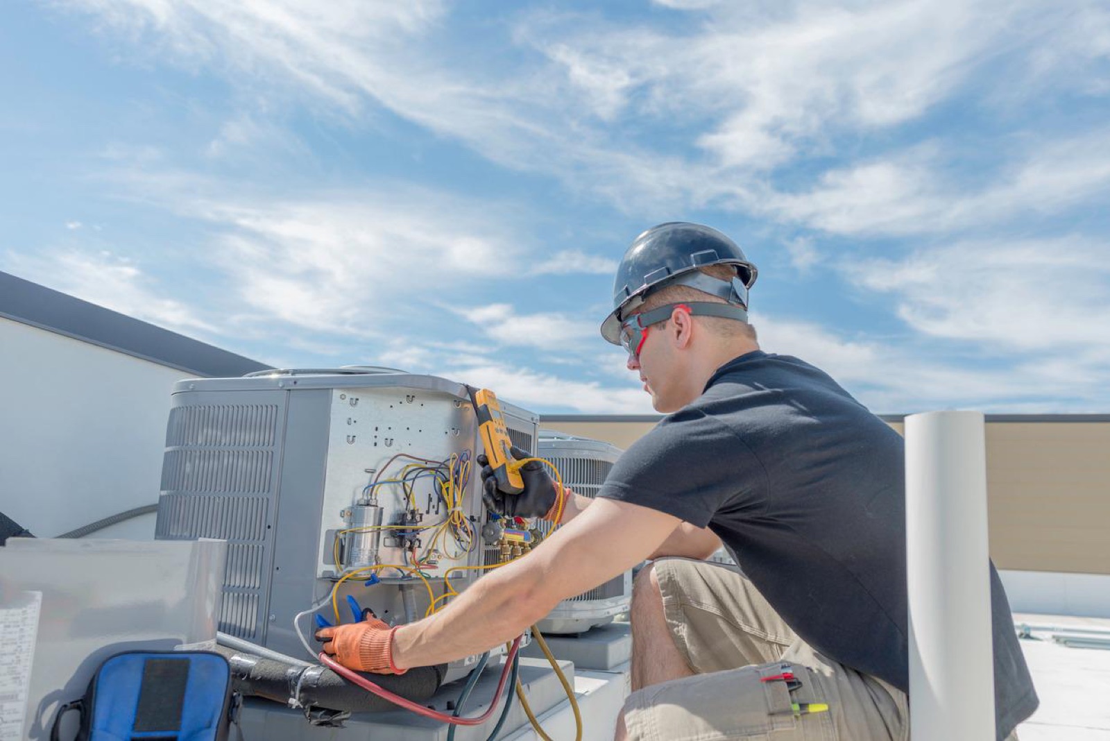 Climate Mechanics technician checking a rooftop AC unit on a sunny day