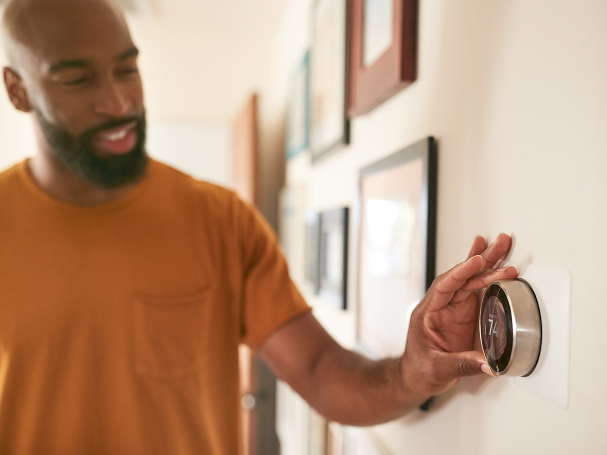 Man adjusting the thermostat in his house